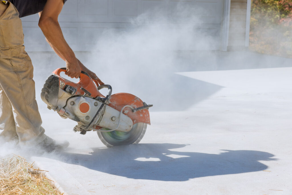 Worker cuts with working diamond bladed cut off saw to concrete paving sidewalk